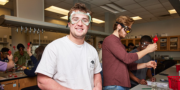 Middle Georgia State University students wearing safety goggles and using pipettes while working together in a science laboratory.